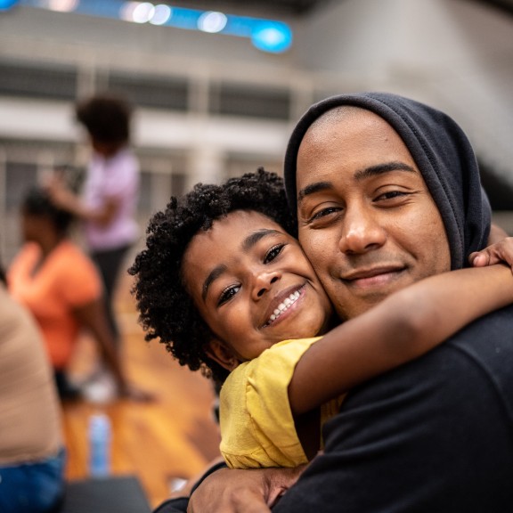 Child has arms around adult neck in a hug