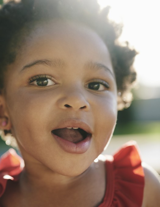 Close up of young child's face with sun shining from behind their head