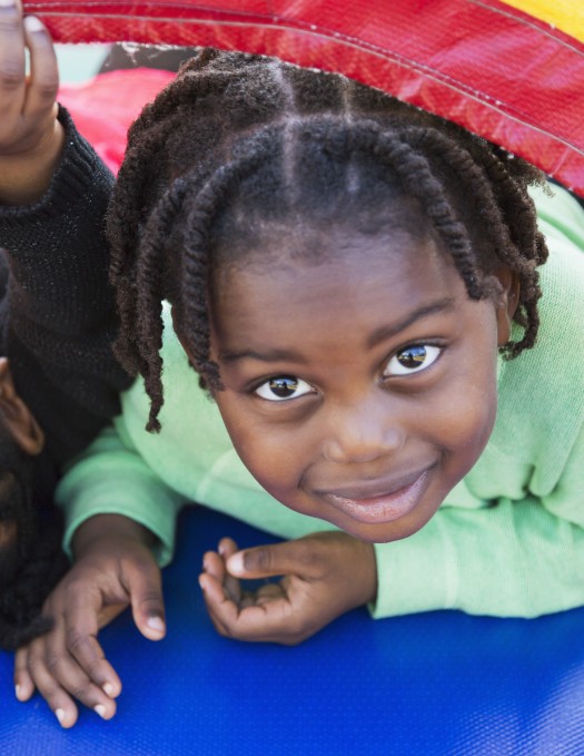 Two young children playing under a colorful nylon blanket or parachute